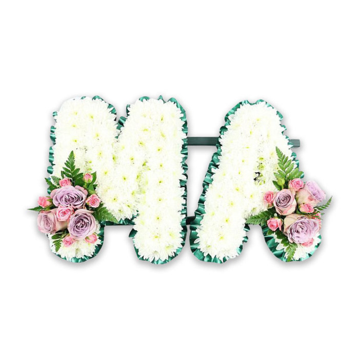 This image shows a carefully designed floral funeral tribute that spells out the word MA, captured as if for an online catalogue from a local Epping florist. The two capital letters stand side by side against a pure white background, giving full focus to the flowers and the craftsmanship. Each letter is completely covered in small, pristine white chrysanthemums, arranged so closely that they form a continuous, cushion-like surface. Every bloom is at the same gentle height, creating a uniform, soft texture that seems almost touchable. Encircling both the M and the A is a band of vivid emerald green ribbon, pleated and ruffled with precision to create a neat, scalloped frame. This border traces every line, from the pointed peaks of the M to the open triangle of the A, providing strong definition and a stylish contrast to the white petals. At the base of the left side of the M and the right side of the A, two balanced floral clusters bring in soft, romantic colour. Here, pastel pink roses and soft lilac or lavender roses are grouped together, some fully open and others still gently cupped. Among them, pink spray roses and small buds add texture and depth. A single, graceful fern frond and sprigs of fresh greenery fan out from each cluster, giving a nod to the natural woodland feel that resonates with the green spaces around Epping. The entire composition suggests a tender, personalised farewell, perhaps for a beloved mum or grandmother known as Ma. The restrained palette of white, green, pink, and lilac conveys peace, reverence, and affection, ideal for a memorial service, crematorium chapel, or home wake where family and friends gather to say their last goodbyes.