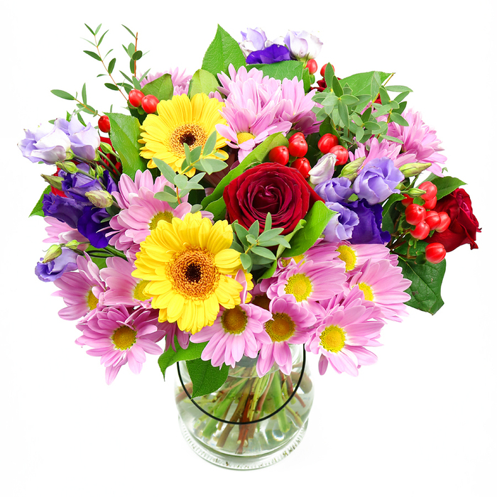 A lavish bouquet of mixed garden-style blooms is showcased in a transparent glass vase, placed before a pure white backdrop so the colours and forms can truly sing. At the centre, layers of deep red roses unfold in soft spirals, their velvety texture giving the arrangement an air of timeless affection. Close by, bold yellow gerbera daisies with rich brown-orange centres beam outward, instantly lifting the mood, much like morning sunshine filtering over the rooftops near Epping station. Encircling these bold focal flowers, generous clusters of pastel pink and lavender daisies or chrysanthemums create a halo of gentle colour. Each flower is made up of fine, overlapping petals around tiny yellow hearts, building up a cushion of texture that softens the overall design. Weaving through the daisies, elegant stems of purple and lilac lisianthus rise, their bell-shaped blossoms and slightly ruffled edges lending a graceful, almost whimsical note that echoes the peaceful calm of nearby Epping Forest glades. Bright red hypericum berries are scattered thoughtfully throughout, their smooth, rounded surfaces catching the light like small berries freshly gathered from a hedgerow, adding both contrast and charm. Surrounding all the blooms is a rich mix of foliage in varying shades of green, from darker, broad leaves that anchor the design to lighter, more delicate shoots that add height and movement. The clear vase reveals the neatly aligned stems and crystal-clear water, evidence of professional floristry and careful conditioning. This vibrant, joyful composition feels perfect for marking birthdays, thank-yous, or housewarmings across Epping, bringing a touch of local garden beauty indoors with warmth and sincerity.