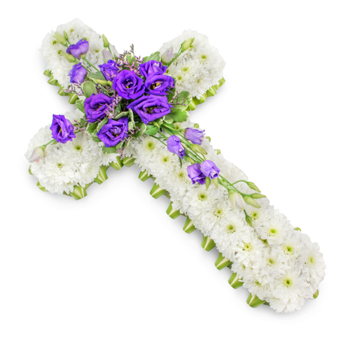 A refined floral cross tribute, intended for a funeral or memorial, is shown against a pure white studio background, allowing every detail of the design to stand out with clarity. The cross is fully covered with fresh white spray chrysanthemums, placed so closely together that no gaps in the foliage can be seen. Each bloom is small and delicate, with a faint green centre, and together they create a smooth, cushion-like texture that suggests peace, purity, and gentle support. Along the outer edge of the cross, a narrow line of vivid lime-green ribbon runs cleanly from top to bottom and side to side, neatly defining the silhouette and adding a subtle, modern contrast. At the heart of the cross, a prominent grouping of deep purple lisianthus forms the main focal point. The lisianthus petals are layered and softly ruffled, some blooms fully open while others remain elegantly cupped, and they are intertwined with slender stems of light green foliage and tiny, airy filler flowers. A few lisianthus buds and blossoms extend from this central cluster, travelling diagonally across and down the lower portion of the cross, giving the design a graceful sense of movement, like a gentle stream of colour flowing downward. The lighting is bright yet soft, with a faint shadow cast beneath the cross for three-dimensional effect. This floral cross would be a fitting expression of sympathy and Christian faith for services in Epping or surrounding hamlets, offering a dignified, comforting presence beside a coffin, at the front of a church, or placed quietly at a graveside.