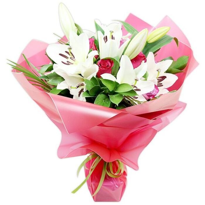 A hand-crafted bouquet of white lilies and red roses is captured in sharp detail against a clean white backdrop, showcasing the skill of a local Epping florist. At the heart of the arrangement, several large Oriental lilies unfurl like graceful stars, each bloom formed of thick, slightly curved white petals with gently ruffled edges. Their centres are marked by dark reddish-brown anthers perched on slender filaments, a dramatic contrast that draws the eye inward. Intermixed with these fully opened flowers are a few elongated lily buds, their pale green casings still closed around the petals, hinting at future blossoms and lending the bouquet a sense of movement and time. Clustered between the lilies are compact red roses, many still in tight bud with overlapping velvety petals, while a few are starting to open into classic cup-shaped blooms, their deep crimson tone intensifying the romantic character of the arrangement. Surrounding the blooms is an abundance of rich green foliage-broad, glossy leaves layered for depth, and narrow, grass-like strands that arch and twist softly, adding texture much like the greenery seen in the gardens around Epping, Theydon Mount, and North Weald. The stems are wrapped in a thick sweep of shiny bright pink cellophane, its semi-translucent surface forming gentle waves and folds that shimmer under the light, creating a glamorous frame for the flowers. At the base, a delicate strand of lime green ribbon is tied securely, its small bow and trailing ends introducing a lively, unexpected accent. The bouquet exudes a feeling of love, gratitude, and celebration, making it a fitting choice for birthdays, anniversaries, or a thoughtful delivery to a home near Epping Forest or along the High Street.