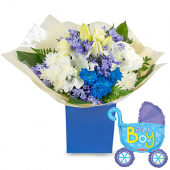 A carefully composed celebration of new life, arranged with the quiet confidence of a local Epping florist: a generous, round bouquet nestles in a deep, royal-blue rectangular presentation box, photographed on a clean white surface so every hue reads clearly. The arrangement balances classic whites and spirited blues-silky white roses at the centre, elegant white lilies partly in bud to suggest beginnings, and full white chrysanthemums that bring a soft, textural base. Bright, electric-blue chrysanthemums punctuate the bouquet, their saturated petals forming a vibrant core that draws the eye, while clusters of soft lavender or periwinkle bell-shaped blooms-reminiscent of hyacinth-add a subtle, powdery aroma and gentle contrast. Fresh green leaves and delicate fern fronds weave through the blooms, lending structure and a garden-fresh scent. The stems are wrapped in crinkled cream-coloured paper gathered at the base, creating a tactile, gift-like finish. Floating to the right, a light-blue foil baby carriage balloon, detailed with darker-blue canopy accents, heart motifs and polka-dotted wheels, declares "It's a Boy" in playful yellow-green letters and completes the celebratory tableau. Prepared with care for newborn visits, baby showers or a surprise on Epping High Street, this bouquet is something our team at Flowers Epping would happily ready for same-day local delivery across Epping and nearby Theydon Bois, Loughton and Buckhurst Hill-fresh, fragrant, and unmistakably joyful.