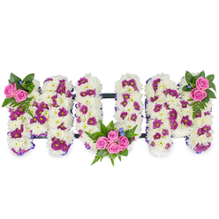 Carefully sculpted into bold, three-dimensional letters spelling MUM, this sympathy tribute sits against a plain white background so each bloom and texture can be read by sight or touch. The foundation of every letter is a generous mass of pristine white chrysanthemums - small, densely packed heads that form a soft, cushiony face and give the arrangement a sense of serenity and purity. Woven through the white are rich magenta and deep purple spray chrysanthemums which create a subtle patterned effect and introduce shadow and contrast across the letter surfaces. Bright pink spray roses are placed as tender focal points: a neat cluster decorates the upper left of the first M, a more abundant posy curves into the lower part of the U, and a corresponding cluster balances the upper right of the final M. Sprigs of dark green foliage, including delicate fern fronds, provide cooling colour and sculptural movement around each rose group, while tiny blue accent flowers are dotted discreetly for a soft, cool highlight. Fine, dark horizontal bars link the letters, adding discreet structure, and a slim purple ribbon trims their edges for a refined finish. The arrangement conveys careful craftsmanship - the kind of personalised tribute a florist from Flowers Epping would prepare for a service at a local funeral home or a memorial gathering beside Epping Forest - a floral embrace that speaks of loss, love, and tender remembrance.