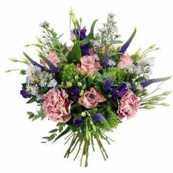 Presented against a clean white background, this hand-tied bouquet feels like a polished snapshot of modern floral artistry, the kind you might receive as a surprise delivery at an Epping High Street office or a cosy home near Epping Forest. At first glance, soft pink and mauve roses draw the eye, their layered petals opening in spirals from deeper rosy centres to gently blushed, almost ivory edges. They sit alongside plush carnations in complementary dusty rose and mauve tones, each bloom filled with fine ruffles that add a tactile, almost fabric-like richness. Rising through the arrangement are elegant spires of indigo and violet Veronica, their slim, tapering forms giving the bouquet a vertical rhythm and a slightly wild, meadow-inspired character. Around them, clusters of purple lisianthus and small aster-like flowers in pale lavender and periwinkle create a halo of dainty blossoms, each tiny petal softening the overall design. Lush greenery wraps around and between the flowers: cool eucalyptus leaves with a silvery cast, more traditional garden foliage, and pops of bright, chartreuse-green filler that echo the vivid new growth you see in local Epping parks in spring. The bouquet is shaped into a rounded, full dome, with every stem placed to balance colour, texture, and height, and the neatly trimmed stems are visible at the base, secured in a natural, hand-tied finish. The mood is one of thoughtful celebration and gentle romance, making this arrangement ideal for birthdays, anniversaries, get-well wishes, or simply bringing a touch of refined colour into everyday life in and around Epping.