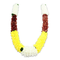 This U-shaped traditional floral garland is presented on a clean white field, photographed to reveal both its colour play and the fine craftsmanship behind each clustered bloom. Each symmetrical arm begins with a thick band of soft, creamy white flowers-small, dense petals that suggest chrysanthemum or jasmine shapes-followed by a shorter, compact segment of deep maroon or reddish-brown fabric blooms that add weight and reverence to the upper curve. Below that, the garland opens into a long, exuberant sweep of bright yellow blooms, their layered petals packed closely to achieve a plush, comforting surface that reads like a living textile. At the bottom centre a larger mound of white chrysanthemum-like flowers forms the focal knot of the design, where the yellow arcs meet and the eye is gently rested; tiny dark green leaf accents are placed between the colour bands to give natural contrast and rhythmic pauses along the composition. The materials are clearly artificial-soft fabric petals, carefully wired-yet the visual rhythm and density speak of hours spent by a practiced hand. For local customers in Epping and neighbouring villages like Theydon Bois and Coopersale, this garland carries familiar ceremonial meanings-purity, devotion, prosperity-and would be chosen for puja, temple offerings, Diwali displays, or as a dignified honour at weddings. The photograph's neutral background and soft shadowing make the textures and cultural intent of the piece immediately legible, a testament to traditional form crafted for contemporary community rituals.