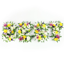 Presented against a stark white studio background, this substantial floral lettering spells "BEST" in four individual, three-dimensional characters crafted from an abundance of freshly cut flowers and lush foliage. Dominant notes of sunshine yellow-seen in long-stemmed roses and cheerful gerbera daisies-are balanced by creamy white chrysanthemum-type flowers and velvety spray carnations, producing a bright, comforting palette. Deeper accents of soft lavender and rich purple lisianthus are tucked into the composition to add thoughtful contrast and visual depth, while pops of vivid magenta-pink from small spray roses or carnations lift the arrangement with joyful energy. Fine clusters of pale green and white filler flowers provide subtle texture and help the eye travel across each letter; generous fern fronds frame and soften the shapes, their dark green fronds giving a natural, leafy silhouette. Where the blooms part slightly you can glimpse the dark green or muted metal support rails that keep each letter structurally sound. Shot front-on with clear, balanced light, every petal shadow and glossy leaf is visible, evoking the fresh, slightly sweet scent of roses layered with the earthy green of ferns. As a local florist piece intended for sympathy or celebration alike, this tribute could be delivered to services at nearby venues, from Epping High Street chapels to gatherings in the shade of Epping Forest. Flowers Epping prepares such hand-crafted memorials with steady hands and an eye for proportion, offering careful placement and local delivery across the Epping area.