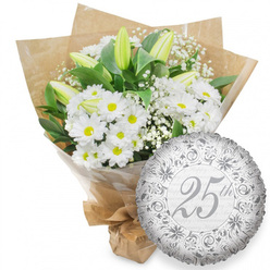 A refined silver anniversary gift is set against a bright white background, featuring a lush white bouquet and an elegant foil balloon that would look perfectly at home in an Epping living room prepared for a special celebration. At the heart of the composition, numerous white chrysanthemum daisies cluster together, each round bloom centred with a warm, sunny yellow eye that adds a gentle touch of colour. Rising above and through them are sleek white lily buds, long and tapering, their petals still mostly closed with a subtle wash of pale green hinting at the freshness of early morning deliveries. Tiny stars of white baby's breath weave between the larger flowers, creating an airy veil that softens the bouquet's outline. Deep emerald foliage fans out behind the whites, giving structure and a rich, natural backdrop, reminiscent of the greenery around Stonards Hill and the edges of Epping Forest. The stems are wrapped snugly in clear cellophane and then embraced by rustic brown kraft paper, folded with care so that its texture and gentle creases are clearly visible. The wrapping is gathered and tied at the base, suggesting the bouquet has just been finished by an experienced local florist. Nestled to the lower right is a round silver foil balloon, its surface shining with a mirror-like sheen. A decorative border of scrolling patterns and floral flourishes encircles the central message "25th" in flowing script, while the phrase "Happy Anniversary" drifts softly across the background in pale grey. The harmonious pairing of classic white flowers and silver detailing quietly celebrates a quarter-century of love, ideal for a Silver Anniversary surprise delivered anywhere around Epping.