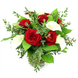 In this image, a beautifully balanced bouquet of red roses and white calla lilies is arranged with the care and precision you might find in a small Epping flower shop just off the High Street. The composition is full and rounded, placed in a clear cylindrical glass vase filled with fresh water, its stems neatly aligned so they form a tidy, green column beneath the blooms. At the top of the arrangement, six or seven red roses open fully, their velvety petals forming intricate spirals that convey depth and softness at the same time, each rose a rich crimson that suggests enduring romance and heartfelt emotion. Slender white calla lilies rise gracefully between the roses, their trumpet-shaped petals curling back as though sculpted from ivory, revealing a warm, yellowish spadix that adds a subtle inner glow. The lilies provide a serene counterpoint to the intensity of the roses, creating a feeling of harmony, like a calm evening walk through Epping Forest after a busy day. Surrounding the central flowers, an array of mixed greenery fills out the arrangement: eucalyptus sprigs with slender, slightly rounded leaves and a soft blue-green tint arch outward, adding a gentle, airy texture, while broader, glossy dark-green leaves anchor the design and frame the red and white blooms. All of this is set against a pure white background, under bright, even lighting that makes every colour vivid and every texture clear-the gleam on the lily petals, the matte softness of the rose, the delicate veins on each leaf. This bouquet feels ideal for marking a special anniversary, a proposal, or a meaningful celebration at home in Epping or nearby Theydon Bois.