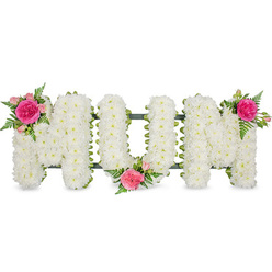 A tender funeral flower arrangement forms the word MUM in striking capital block letters, set against a bright, uncluttered white background that lets the details shine. Each letter is densely packed with countless small white chrysanthemum heads, laid so close together they create a velvety, cloud-like surface, symbolising innocence, peace, and the quiet strength of a mother's love. Along the underside of the letters, a dark green ribbon edge and the discreet support frame peek through, lending both stability and a gentle outline that makes the shapes easy to read, even from a distance in a church or crematorium chapel around Epping. Colour is introduced with three carefully placed accent clusters. On the upper left of the first M, a bright fuchsia garden rose unfurls among paler pink spray roses and delicate fern fronds, the petals full and softly curled. Another cluster rests in the lower central dip of the U, its roses and buds cradled within the white blooms, like a small, beating heart in the middle of the tribute. The final grouping crowns the upper right of the second M, mirroring the first and bringing a graceful sense of symmetry. The interplay of crisp white and vivid pink, along with the feathery green foliage, gives the design a gentle movement, as though a breeze is passing through a garden near Epping High Street. This floral lettering feels deeply personal, the kind of bespoke memorial a family might choose to say thank you and goodbye to their mum, offering a message of love, remembrance, and respect crafted entirely in fresh, fragrant flowers.
