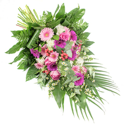 Set against a clean white background, this hand-tied funeral spray flows diagonally from the upper left to the lower right, like a quiet farewell carried on a breeze across Epping's open fields. The composition is rich and abundant, built around large gerbera daisies in shades of delicate pastel pink and bolder fuchsia and magenta. Their broad, cheerful faces bring a note of warmth and gratitude to the tribute. Interlaced among them, classic pink roses, with their tightly furled, velvety petals, introduce a sense of romance and deep affection, as though each bloom holds a cherished memory. Soft, ruffled white flowers, likely carnations or petite chrysanthemums, lighten the palette and add a cushion of texture, while clusters of tiny white daisy-like blossoms thread through the arrangement, echoing the simple charm of daisies found along country paths near Epping Forest. Bright red hypericum berries punctuate the spray with small bursts of colour, creating contrast and a hint of vitality amidst the softness. The flowers rest on a luxurious bed of greenery: broad, glossy dark leaves, airy green ferns, and rounded silvery eucalyptus foliage that suggests a fresh, calming scent. Long, sweeping palm fronds extend from the lower right, reinforcing the cascading movement and drawing the eye gently downward. At the upper left, the stems are gathered and neatly bound, showcasing the careful handwork of a skilled local florist. The overall mood is one of respectful condolence and quiet strength, a beautiful sympathy design suitable for delivery to services and homes throughout Epping, offering comfort and honour in a time of loss.