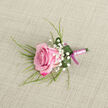 On a gently woven, light beige surface reminiscent of natural linen, a carefully crafted boutonniere takes centre stage, composed around a single pink rose that leans slightly on the diagonal. The rose itself is full of nuance: its outer petals are washed in rich magenta and fuchsia, while the colour softens gradually toward the centre into a tender blush, giving the impression of a flower just opening to the day. Around it, tiny white blooms of baby's breath form airy clusters, each minuscule flower adding a sense of lightness, like a soft mist around the main rose. Wispy, grass-like greenery extends from behind, their slender lines creating graceful arcs that echo the natural movement of flowers growing along the paths near Epping Forest. A single, broader leaf is artfully curled around the base, a deep green cradle dotted with a few bright droplets of water that hint at cool morning preparation and careful hydration. The stems are bound with a smooth satin ribbon in a pale, almost blush-pink tone, wrapped with precision, and finished with a dainty bow in deeper pink at the base, creating a subtle two-tone effect. The neutral background and soft, even lighting allow every texture-from velvety petal to satiny ribbon-to be seen clearly, while the overall mood is one of quiet romance and polished elegance. This boutonniere would feel perfectly at home on a groom's lapel at an intimate Epping wedding or a formal event at one of the local country venues, embodying both tradition and contemporary floral design.