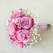 A joyful and romantic bouquet crafted by the skilled hands of an Epping florist, this compact arrangement bursts with colour and graceful beauty. It features five radiant roses whose petals transition from gentle lavender at the heart to vibrant fuchsia-pink at the edges, combining classic romance with a modern twist. Delicate baby's breath, with its tiny white blossoms, is scattered throughout, offering a textured, airy contrast to the rich tones of the roses. The stems are neatly bound and wrapped in a deep magenta ribbon, subtly sparkling in the daylight and harmoniously echoing the roses' hues. Encircling the handle, iridescent pearls catch the light, imparting an extra sense of celebration and refinement. The natural green-brown tips of the stems emerge just below the decorative wrapping, adding to the bouquet's fresh, hand-tied authenticity. Set diagonally on a soft, off-white linen cloth-reminiscent of elegant table settings at local Epping venues-the bouquet's vibrant shades pop against the neutral backdrop. Whether destined for a wedding at St John's or presented as an anniversary gift at one of Epping's charming inns, this arrangement radiates happiness and love. Its tender composition and lively colours make it an emblem of cherished moments, expertly delivered by Flowers Epping to the heart of Essex.