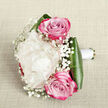 Resting on a softly textured off-white fabric, this hand-tied bouquet is captured from a slightly raised angle that lets you almost feel its shape in your hands. At the centre sits a single, luxuriously full creamy white peony, its many ruffled petals opening in a soft, billowing dome that suggests quiet confidence and grace. Framing it, two pink roses draw the eye, one poised above and the other below, their petals spiralling tightly from the heart and gradually deepening into rich magenta tones at the outer edges, like the warm glow of an Epping sunset beyond the rooftops near the station. Threaded throughout are airy clusters of white baby's breath, each tiny bloom adding a gentle sparkle and cloud-like softness that lightens the whole design. Broad, deep green leaves encircle the base, their smooth, glossy surfaces giving structure and a sense of groundedness, much like the tall trees lining the paths into Epping Forest. The stems are neatly wrapped in a simple white satin ribbon, hinting at a bouquet intended to be held during a wedding, civil ceremony, or intimate vow renewal in one of Epping's local venues. The lighting is soft and natural, enhancing the creamy whites, warm pinks, and rich greens, while the neutral background keeps the focus entirely on the flowers. This arrangement feels like a carefully considered gesture of affection and celebration, echoing the elegant, understated style that many couples around Epping choose for their special day.