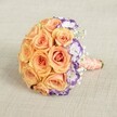 Set against a soft, neutral backdrop reminiscent of Epping's tranquil interiors, this elegantly crafted bridal bouquet presents a striking dome of plump peach, coral, and apricot roses, their petals swirling together in an invitingly plush texture. A dramatic visual twist comes from the inclusion of crisp lisianthus blooms, their creamy petals edged boldly in purple, adding an artistic contrast and depth akin to the gentle dusk hues seen across Epping's countryside. Lacy sprigs of baby's breath are scattered with intention, lending a weightless, romantic lift to the composition and further brightening the arrangement's palette. The stems, secured in a lustrous peach satin ribbon and finished with a winding of creamy pearl beads, create a handle that feels graceful and refined-perfect for bridal moments or elegant gift-giving throughout the town. The design's blend of warm and cool tones speaks of romance and creativity, perfect for spring and summer celebrations, milestone birthdays, or local weddings in Epping's cherished venues. The bouquet's balanced elegance captures not just the visual beauty but the emotional heart of a special day: a keepsake memory, lovingly prepared by expert hands for life's most meaningful events.