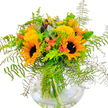 Capturing the vibrant spirit of Epping, this exuberant bouquet bursts with heartfelt warmth and natural beauty. Sunflowers take center stage, their immense, golden-yellow blooms gracing the arrangement with the same exuberance seen in Epping's summer parks. Especially eye-catching are two prominent sunflowers, their inviting dark centers surrounded by a radiant corona of petals, evoking the joy of sun-drenched afternoons. Alongside these, clusters of soft yellow filler flowers and whimsical coral-orange accents-echoes of tulips or budding hypericum-introduce playful movement and lively contrast. Draping ferns in deep green, reminiscent of the foliage found around Epping Forest, cascade gracefully, while silver-tinged eucalyptus and lime-green sprigs round out the ensemble with contemporary flair. The modern, round glass vase cradles the bouquet, displaying fresh-cut stems immersed in clear water, a testament to local florist care and attention. Gentle sunlight highlights every texture-the softness of petals, the feathery ferns, and the interplay of light and shadow-imbuing the display with an uplifting aura suited for any celebration, from birthdays to simple 'thinking of you' gestures. Whether delivered to homes near High Road or as a vibrant centerpiece on market day, this bouquet carries a breath of Epping's cherished nature indoors, shining with cheerful promise and time-honored craftsmanship.