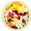 A bird's-eye view focuses on a round, pale yellow ceramic bowl, its rim just visible as it cradles a lavish bed of fresh flower petals arranged for a quiet, dignified tribute in Epping. The bowl's surface is a soft cream-yellow, warm but understated, allowing the petals within to hold the eye. Inside, generous rose petals in velvety crimson red, bright golden yellow, and delicate peachy apricot fill the space in gentle, overlapping layers, reminiscent of scattered confetti yet carrying a more solemn, reflective tone. Threaded among them are numerous small white florets, likely hydrangea or a similar bloom, their tiny, ruffled petals forming cool, bright patches of contrast that soften the richer colours. The petals appear loosely poured rather than formally arranged, giving the display an organic, almost ritualistic quality, as if they might be lifted and scattered in final farewell over a grave or memorial site near Epping Forest or one of the town's peaceful cemeteries. The overall impression is one of tender abundance and calm: the reds speak of deep love and remembrance, the yellows and peaches evoke the warmth of shared stories, and the whites suggest purity and rest. You can imagine the gentle rustle when fingers brush through the petals, and the soft rose scent rising in the stillness of a chapel. This simple yet evocative bowl of petals would sit beautifully beside a condolence book, a framed photograph, or other sympathy flowers, bringing colour, texture, and a quiet sense of care to moments of mourning.