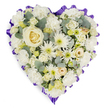 A carefully crafted heart-shaped floral cushion is shown against a bright white background, its gentle colours and thoughtful design evoking the calm of a quiet chapel before a service somewhere near Epping High Street or the green edges of the forest. The heart is completely covered in a serene blend of white, cream, and the softest hints of pale yellow, giving the tribute a soothing, harmonious appearance. Larger ivory and white roses form the main focus, their layered petals unfolding gracefully across the centre and upper curves of the heart. Between them, clusters of small white chrysanthemums and daisy-style spray blooms with pale yellow or light green centres add texture and a gentle inner glow, breaking up the surface with intricate detail. Finer filler flowers, possibly mini carnations or gypsophila in creamy and soft lemon tones, are nestled closely together, creating a full, luxurious feel with no empty patches. Throughout the design, cool-toned, silvery-green foliage-likely eucalyptus or a similar leaf-peeks through the petals, offering depth, contrast, and a suggestion of fresh, clean fragrance, like the air after rain over Epping's open spaces. The entire heart is encircled by a ruffled border of deep lavender or rich purple ribbon, pleated to form gentle waves that frame the flowers and emphasise the heart shape with a dignified band of colour. This classic funeral tribute, similar to pieces often chosen by families in Epping for crematorium or graveside ceremonies, symbolises love, remembrance, and quiet support, offering a tender visual expression of sympathy and respect at a time of loss.
