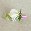 This image shows a finely crafted orchid boutonniere laid on a natural, linen-like fabric in a soft oatmeal shade, the neutral background gently emphasising the polished floral work. At the centre is a pristine white Phalaenopsis orchid, its petals smooth and broad like pieces of fine bone china, opening out with a calm, symmetrical grace. The orchid's throat glows with a subtle wash of yellow-orange and a faint blush of pink, drawing the eye inward to its intricate, sculptural core. Surrounding the main bloom is a cloud of white Gypsophila, or baby's breath, each minuscule flower contributing to a veil of softness that seems to float around the orchid, giving the design a dreamy, romantic lightness. Threaded between these delicate blossoms are slim, vibrant green leaves, carefully placed to create gentle lines of colour that frame and lift the white blooms, much like the fresh foliage you'd see in gardens around Epping or along the paths near Epping Forest. To one side, a slender stem stretches out, bearing three plump pale green orchid buds; they are tightly closed, quietly suggesting future blossoms and echoing the idea of a new chapter, whether in marriage or another milestone celebration. The stems are tidily bound with a lustrous bright pink satin ribbon, wrapped snugly and finished with a small bow whose short tails lie neatly against the fabric. The contrast between the pink ribbon and the pure white flowers adds a touch of playful elegance, making this boutonniere ideal for a groom, groomsman, or prom guest heading out from a home in Epping town centre. The overall mood is refined yet tender, reflecting the practiced hand of an experienced florist and the personal joy of a cherished occasion.