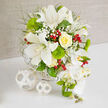 On a pristine white tabletop, an opulent bridal bouquet is displayed like a work of art, its tranquil palette of white, green, and soft yellow standing out gently against a warm beige backdrop, reminiscent of the calm, neutral interiors of homes around Epping. Central to the design are open white Oriental lilies, petal tips elegantly recurved, their faint speckling and exposed stamens providing subtle drama and depth. Just beside them, a perfectly shaped yellow rose unfurls in a tight spiral, creamy petals glowing with a buttery, sunlit tone that adds quiet luxury. Around these focal blooms, airy clusters of white baby's breath drift like fine lace, filling the gaps with a romantic haze. Bright green trick dianthus, rounded and almost moss-like, offer a playful counterpoint to the lilies' smooth surfaces, while soft green foliage threads through the bouquet, giving it a natural, just-gathered feel that could have come from the edges of Epping Forest. Gleaming red hypericum berries punctuate the greens and whites, each cluster like small jewels, bringing a seasonal, almost festive energy ideal for wedding receptions or engagement dinners held near the High Road. On the right, a graceful spray of white Phalaenopsis orchids flows in a gentle cascade, their broad, satin-like petals and emerging green buds adding movement and height. The arrangement is anchored in a white woven basket, its texture echoed by two matching decorative spheres resting on the table, adding a modern styling detail. This thoughtfully composed bouquet, typical of the crafted designs available for wedding flower delivery throughout Epping, embodies contemporary elegance and serene celebration.