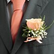 Beneath the gentle glow of Epping's afternoon sun, this timeless boutonniere radiates understated romance and anticipation. Centered is a single blush peach rose-its petals sweetly opening, delicate and buttery, inviting soft light the way dawn visits the edges of Epping Forest. Surrounding this focal bloom, dainty sprigs of baby's breath evoke morning dew on fresh grass near the High Street, their tiny white florets adding lightness and airy texture. Wispy lengths of green foliage rise gracefully, their movement echoing the natural verve found along Stonards Hill. The arrangement is nestled against a sharply tailored charcoal suit, anchored by a neatly tied peach satin ribbon-a quiet, lustrous finish that echoes the partnering tie. Its subtle scent is reminiscent of local garden air after rain, both reassuring and celebratory. As crafted by Flowers Epping, this boutonniere is a token of unity and hope, meant to rest close to the heart on days woven from the moments and memories that define Epping life.