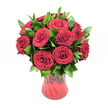 A lush, romantic bouquet of around twelve to fifteen deep crimson red roses stands proudly in a translucent red glass vase, set against a spotless white studio background that makes every colour glow. Each rose is fully open yet still plush at the centre, with velvety petals curling in elegant spirals that create a feeling of softness and depth, like the classic long-stemmed roses you might choose for an anniversary dinner in Epping. The rich ruby tones dominate the arrangement, radiating warmth, passion, and a sense of timeless romance, while the generous collar of dark, glossy green foliage - likely ruscus or a similar leaf - peeks confidently between the blooms. These leaves add texture and shape, their smooth, waxy surfaces catching the light and providing a vivid contrast that makes the red appear even deeper. The vase itself is a striking feature: a red glass container with a gently curving body that narrows towards the base and flares at the rim, its subtle ribbed or undulating texture adding movement as it reflects the light. Through the translucent glass, hints of stems and varying red tones are visible, tying the whole design together. The clean white backdrop suggests a professional florist's studio, the kind of setting you might find behind the scenes at a local shop preparing same-day romantic flower deliveries across Epping High Street and the nearby residential lanes. Overall, the image conveys beauty, devotion, and heartfelt emotion - an ideal visual representation of a luxurious red rose bouquet chosen to celebrate Valentine's Day, a milestone anniversary, or any deeply personal expression of love in and around Epping.