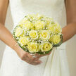 Held close to a bride's heart, this compact bouquet of pale yellow roses reads like a quiet promise-soft, sincere and perfectly formed. Each rose is a study in careful cultivation: petals layered into neat spirals, their buttery hue catching the light with a gentle, satin glow. Interspersed among the roses, sprays of white baby's breath lend a cloud-like softness, their tiny flowers like whispered blessings that lift the visual weight of the composition. Curved blades of glossy green grass wrap the arrangement, creating an architectural collar that both contains and celebrates the delicate blooms. The bouquet sits against cream lace and feels like a quiet sunrise-the scent is subtle, a mingling of light honeyed rose and freshly cut green, enough to suggest intimacy without overpowering. As someone who arranges flowers for weddings around Epping-from small ceremonies on Bell Common to receptions near St. John's Road-I craft pieces to sit beautifully in photographs and to feel comfortable in a bride's hands throughout the day. At Flowers Epping we pay attention to balance and texture, ensuring the bouquet is easy to hold, resilient during travel, and visually balanced close up and at a distance. Whether carried down the aisle at a local church or posed beneath the trees at Epping Forest, this bouquet is meant to whisper devotion: understated, elegant, and thoughtfully composed for moments that will be remembered.