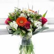 Effortlessly capturing the energy of spring mornings in Epping, this vibrant bouquet is a celebration of freshness and joyful design. Anchored by a luminous tangerine-orange Gerbera daisy-whose rounded petals radiate happiness like a sunbeam across Epping Green-the arrangement comes to life in a clear glass vase where lush stems are immersed in sparkling water. Generous, richly coloured roses in deep magenta and crimson offer a sumptuous contrast, their velvety petals unfolding with grace reminiscent of the blooms found at local markets on Saturday mornings. Around them, white alstroemeria blooms arch outward, their striped petals and delicate speckles curving with the elegance of swans, interlaced with petite, daisy-like white chrysanthemums adding subtle, frothy texture. The bouquet's upper reaches are softened by creamy and pale yellow roses, while the occasional appearance of tiny lavender or purple florets adds understated sophistication and depth. Framed in glossy green foliage-broad leaves cradling the base and slender shoots providing height and movement-this composition feels both abundant and artful. Bathed in soft, natural light, every flower seems full of life and promise, making the bouquet perfect for celebrating birthdays, anniversaries, or sending heartfelt congratulations anywhere in Epping, sharing a timeless message of happiness and renewal.