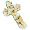 A substantial, cross-shaped floral tribute is shown against a pristine white backdrop, its form completely covered with lush, carefully arranged blossoms. The Christian cross is defined by a thick base of white and creamy ivory flowers, including rounded hydrangea heads and tightly packed roses or spray roses, giving the arrangement a soft yet structured appearance. Scattered along the length and width of the cross are clusters of pastel roses in shades of pale pink, gentle peach, and soft apricot, some in full bloom and others in bud, adding warmth and an understated sense of tenderness. Tiny sprigs of lavender or light purple filler flowers are woven among the petals, offering subtle colour highlights that enrich the overall composition. Around the edges, slender hints of fresh green foliage peek out, outlining the cross and adding a natural contrast to the pale blossoms. The flowers appear fresh and vibrant, as though they have just been arranged for a service at a local church in Epping or delivered to a family home near the High Road for a wake or vigil. The lighting is clear and even, bringing out the creamy tones and soft blush shades while casting a faint shadow that lifts the arrangement from the background. This floral cross feels both peaceful and deeply meaningful, designed as a sympathy tribute to honour a loved one's faith and memory. Its gentle colours and harmonious design evoke comfort, quiet reflection, and the enduring love shared among family and friends during times of farewell.