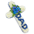 A large, elegant floral cross lies against a spotless white background, its form instantly recognisable as a traditional Christian symbol of remembrance. The entire surface of the cross is built from masses of small, white spray chrysanthemums, their compact blooms pressed closely together to form a thick, cushion-like base that appears soft and tranquil. The border is defined by a rich band of royal blue satin ribbon, carefully gathered and smoothed along every edge, giving the piece a dignified, finished look and providing a striking contrast to the pure white flowers. At the heart of the cross, an eye-catching arrangement of royal blue blossoms draws attention: full-petalled blue carnations mixed with more slender, vertical blue flowers that resemble delphiniums or orchids. These are interlaced with dark green fern fronds and glossy foliage, adding texture and evoking the calming greenery found around Epping's open spaces and woodland borders. On the vertical stem, the word DAD is spelled out using folded and looped segments of the same satin ribbon, each handcrafted letter rising gently from the white chrysanthemum base so it is easy to distinguish. The clean, bright lighting produces only a soft halo of shadow beneath the cross, enhancing its sculpted look without distracting from the floral work. The design feels both personal and reverent, the kind of carefully made tribute that local families in Epping might choose to honour a father at a funeral service, memorial gathering, or burial, expressing love, loss, and gratitude in a single, beautifully composed floral cross.