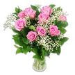 A gracefully arranged bouquet of baby flowers fills the centre of the frame, captured against a bright white background that allows every pink and green detail to shine. At its heart, around ten to twelve pink roses form a full, rounded dome, some blooms open wide to reveal their spiralled centres, others partially closed, giving a sense of freshness and gentle movement. The shades of pink range from pale, almost pastel blush on the outer petals to richer, more confident rosy tones deeper within, echoing the soft, hopeful feeling of celebrating a new baby. Interlaced throughout the roses are fine sprays of white baby's breath, their tiny, cloud-like blossoms creating an airy veil that softens the arrangement and adds a whisper of classic charm. Surrounding the central blooms, lush dark green rose leaves spread outwards, their surfaces smooth and slightly glossy, offering a rich, natural frame that enhances the delicacy of the pink and white flowers. All of this is gathered in a simple, clear glass vase, partially filled with clean water and revealing a tidy grid of green stems, freshly trimmed and fanning out gracefully towards the base. Gentle, even lighting bathes the entire bouquet, creating subtle highlights along each petal edge and lending the roses a velvety texture that suggests they have just been arranged by an experienced local florist in Epping. The overall mood is serene, joyful, and welcoming - a perfect visual for baby girl bouquets, new arrival celebrations, or tender congratulations sent to families across Epping, Coopersale, and nearby villages.