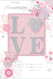 Captured in soft, flattering light, this anniversary card presents a gentle celebration of enduring romance, its colours blending in a soothing harmony of pastel pinks, silvery greys, and creamy whites reminiscent of a delicate bouquet arriving at a doorstep in Epping. At the very centre, the word LOVE stands proud in raised glitter, the letters elegantly shaped and touched with a subtle sparkle. The O is transformed into a shimmering heart, textured in silver so it appears almost jewelled, like a single statement bloom in the middle of a hand-crafted arrangement. Around this central word, an array of blush and mauve-toned flowers opens in a soft, watercolour style, their petals and fine stems sweeping outward in curved, flowing lines that suggest movement and care. Tiny details-scattered petals, graceful swirls, and the suggestion of delicate butterflies-add a sense of airiness and motion, evoking the calm charm of an English spring garden not unlike the peaceful green corners around Epping. The phrases On Our Anniversary and I love you today and always, or similar heartfelt text, are set in an understated, elegant script that appears to float among the blooms rather than sit heavily upon them. The whole card feels poised between intimacy and celebration, much like sharing a quiet toast at home near Epping High Street after flowers have been delivered. Its composition, with the sparkling heart at the centre and the floral garland unfolding around it, captures a shared journey-soft-spoken yet deeply felt-making it an ideal paper companion to an anniversary bouquet sent to mark another year together.